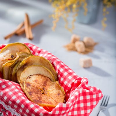 Cinnamon-dusted apple crisps in a rustic basket, perfect for a cozy snack.